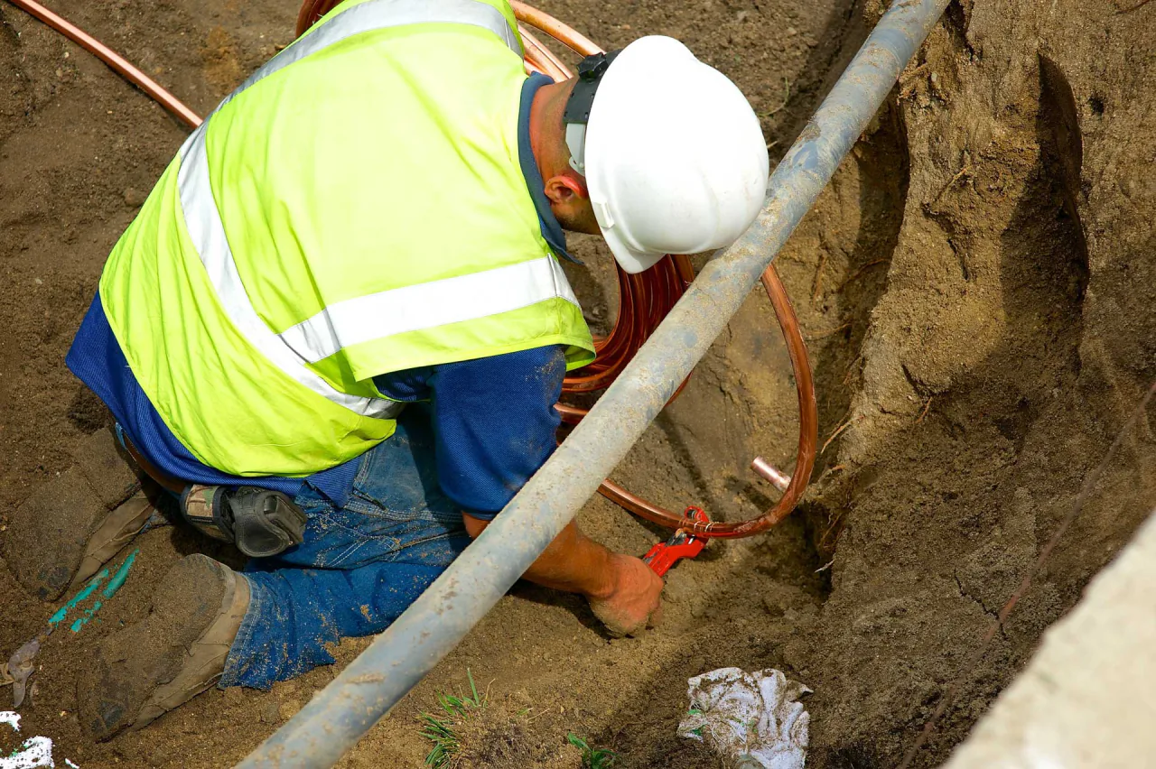 A Bob Frame Plumbing crew member repairing a line in a trench