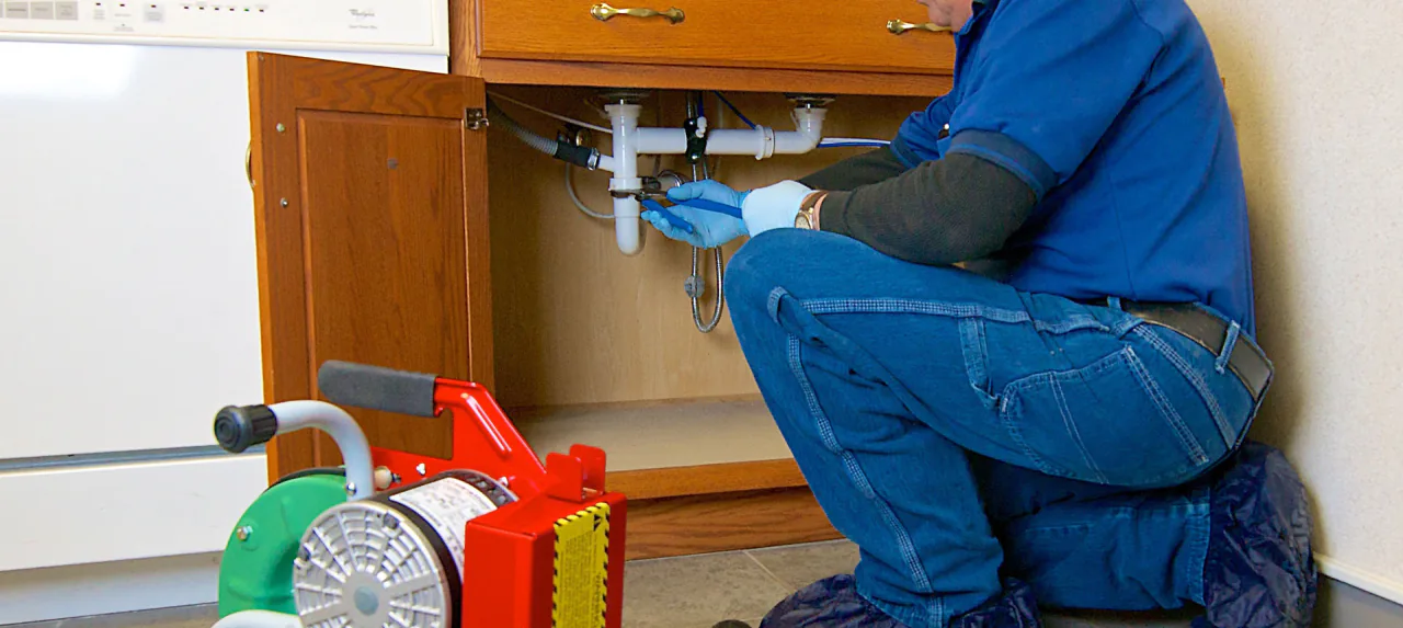 A Bob Frame Plumbing technician working under a kitchen sink