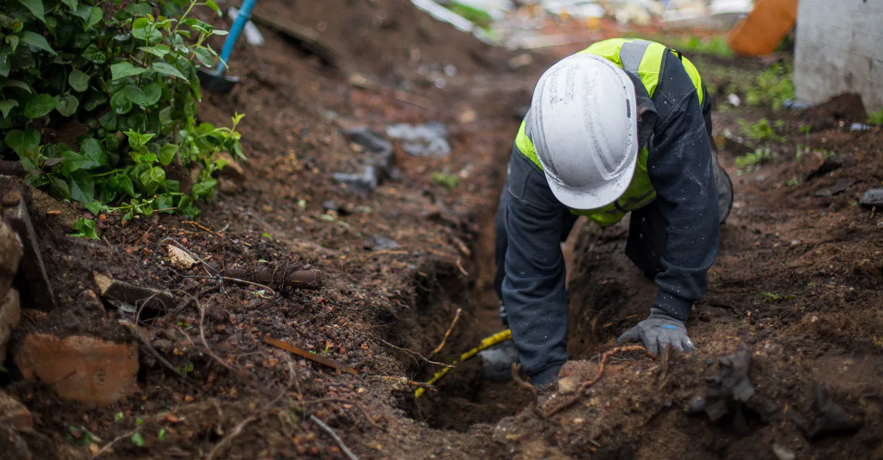 A Bob Frame Plumbing crew member working in a trench